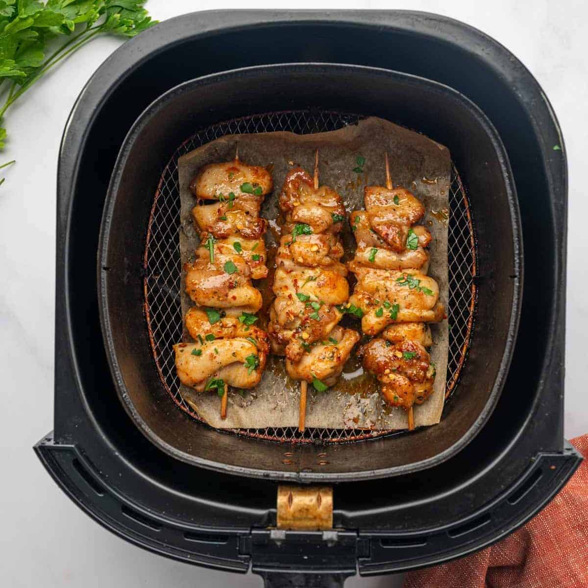 Chicken Skewers Arranged in Air Fryer Basket with Crispy Edges and Juicy Texture. Brushed with butter sauce.