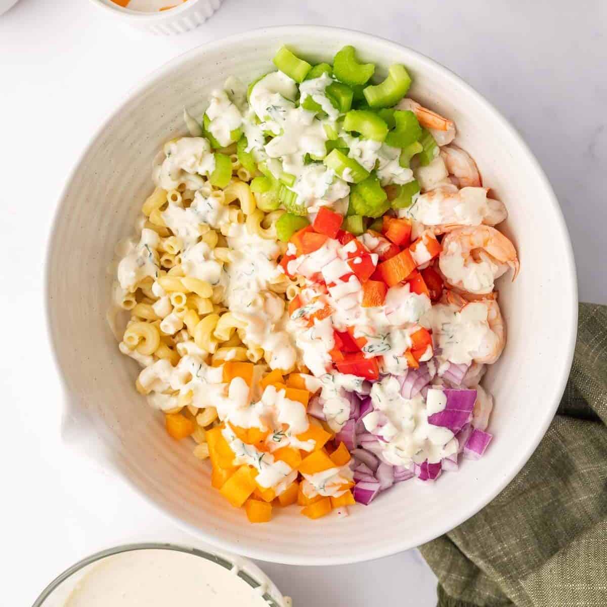 Salad ingredients are layered in a bowl and topped with dressing.