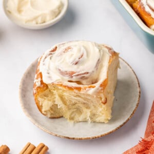 Cream cheese topped cinnamon roll on a plate.