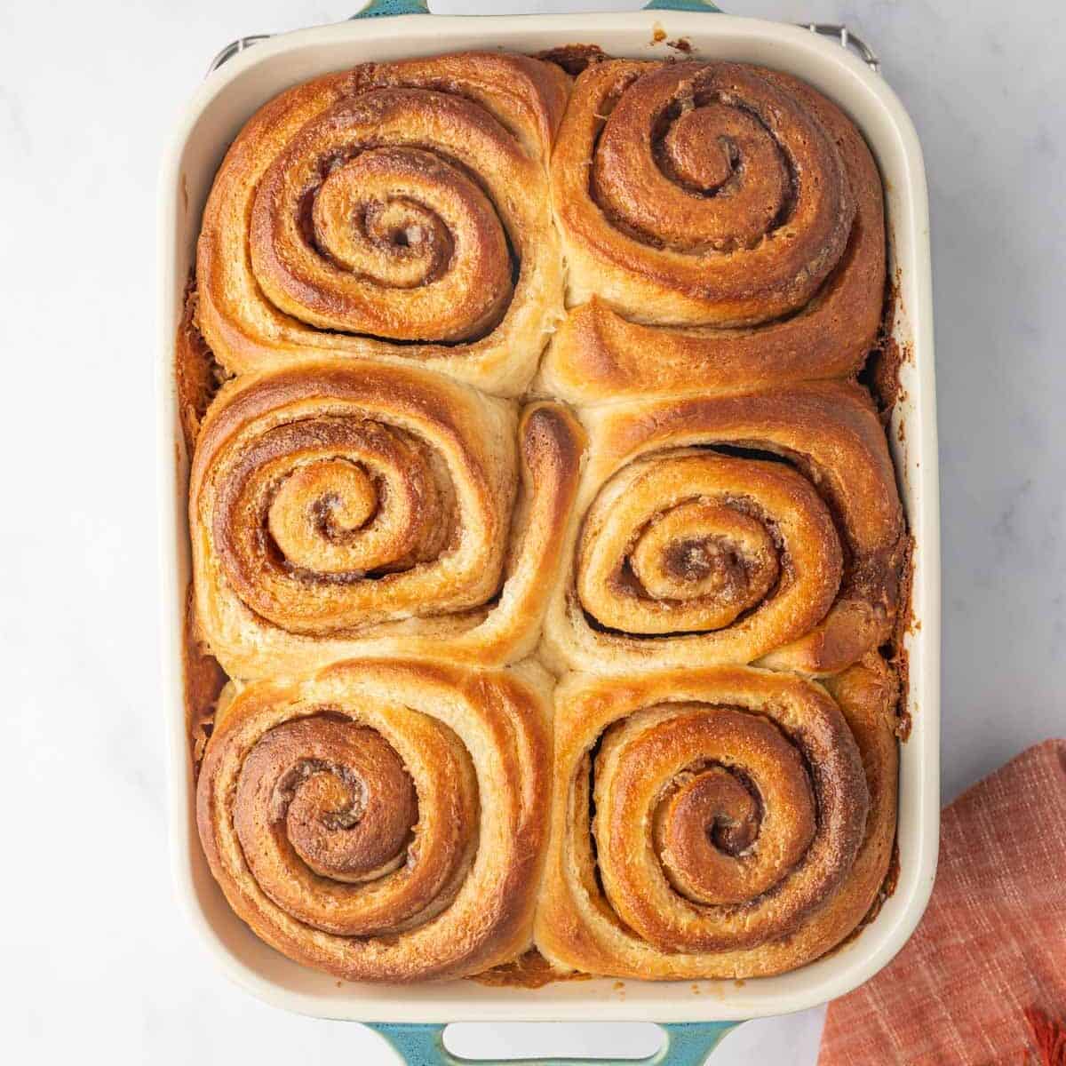 Baked and unfrosted cinnamon rolls in a baking dish.