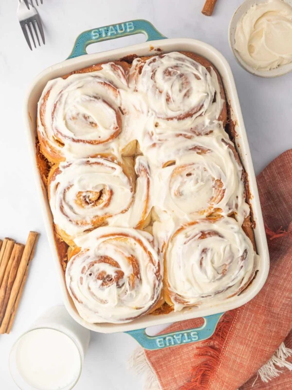 Frosted Cinnamon rolls made with heavy cream in a baking dish.