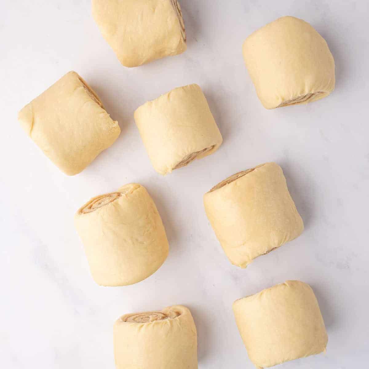 Cinnamon roll dough is cut into individual pieces.