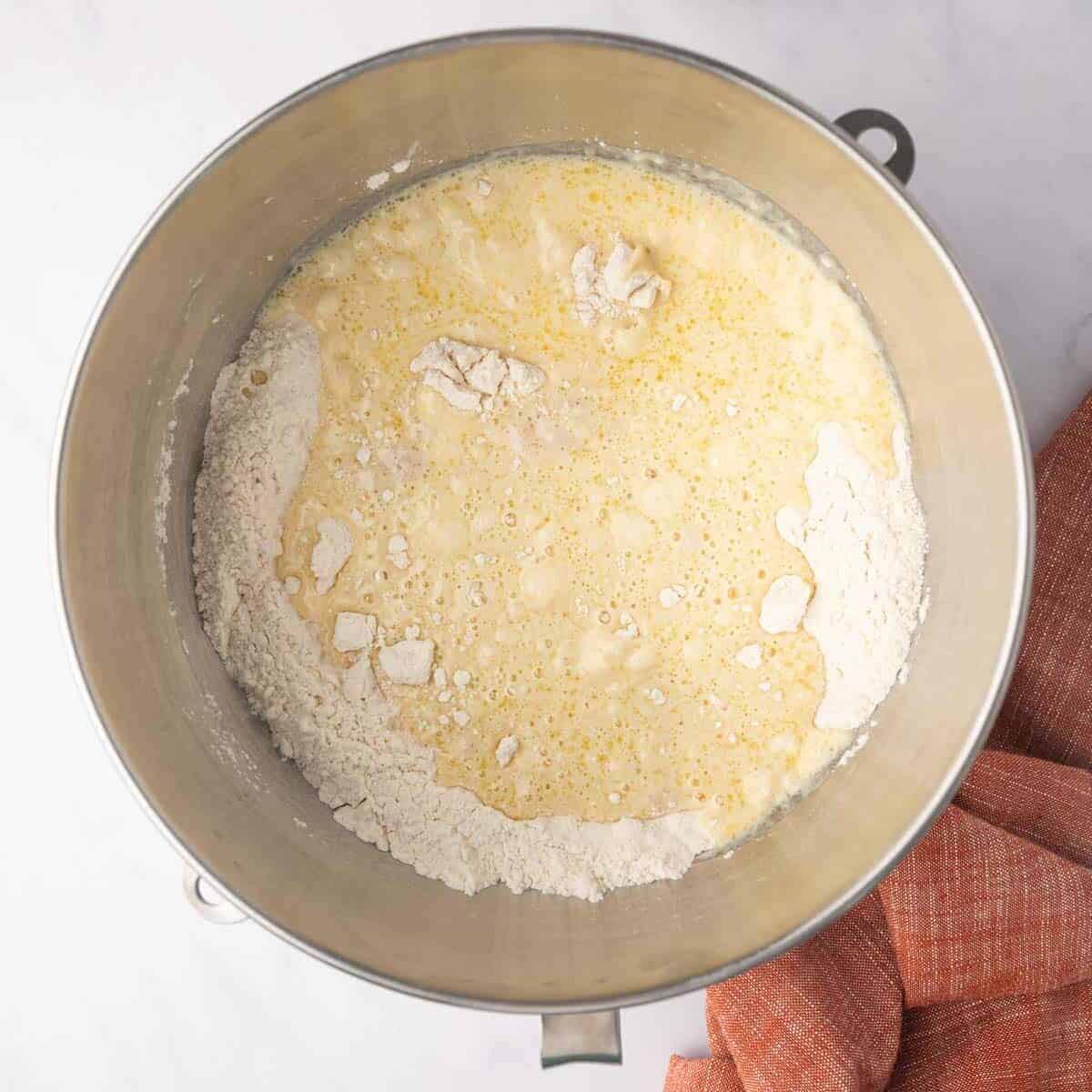 Wet and dry cinnamon rolls are combined in a mixing bowl.