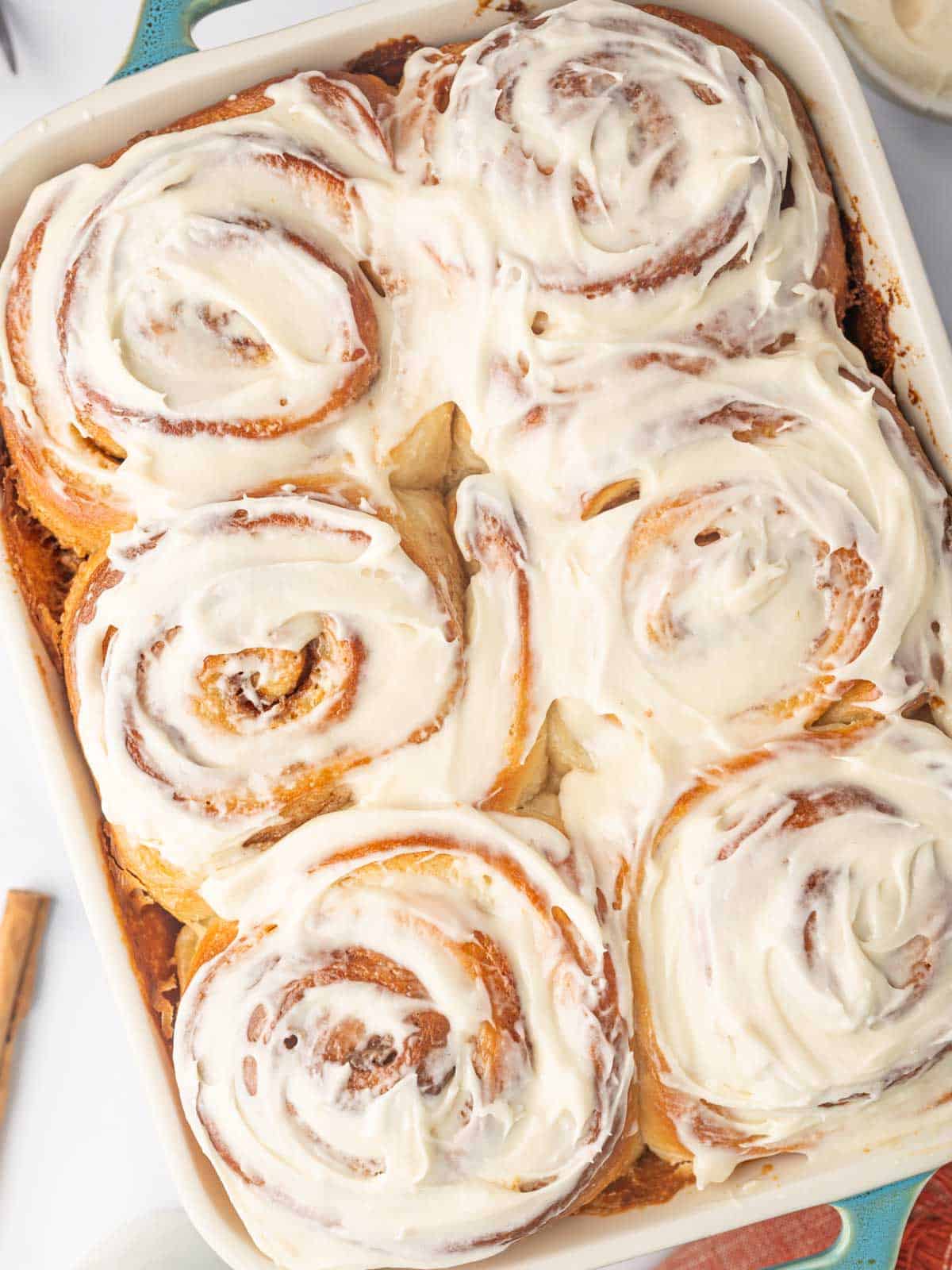Cooked cinnamon rolls spread with cream cheese frostimg.