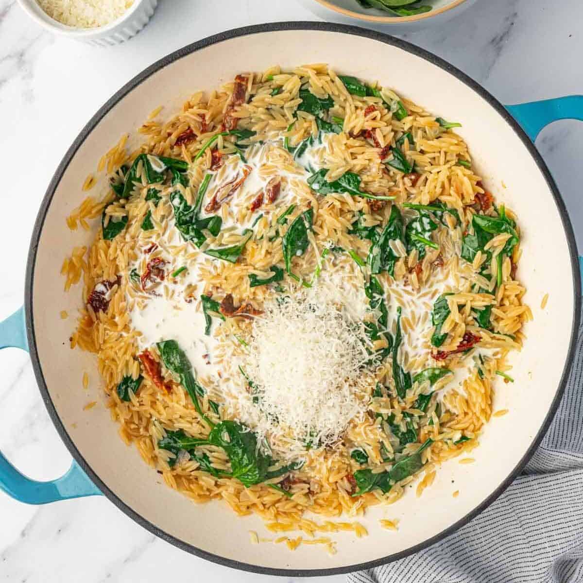 Parmesan cheese is added to a bowl of orzo pasta.