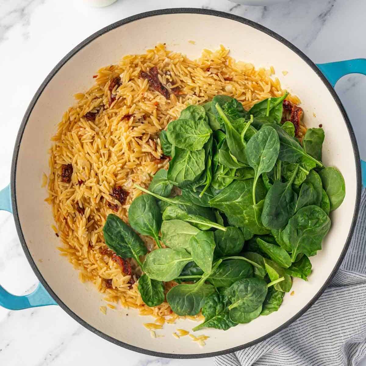 Orzo pasta is mixed with fresh spinach.