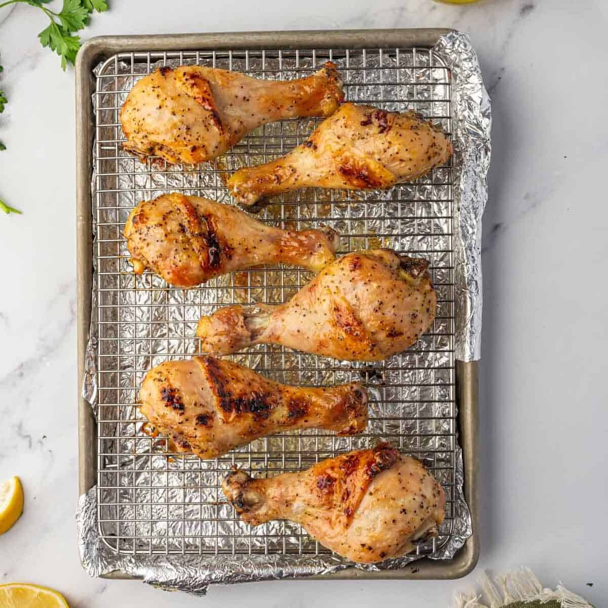 Baked chicken legs on a wire rack over a baking sheet.