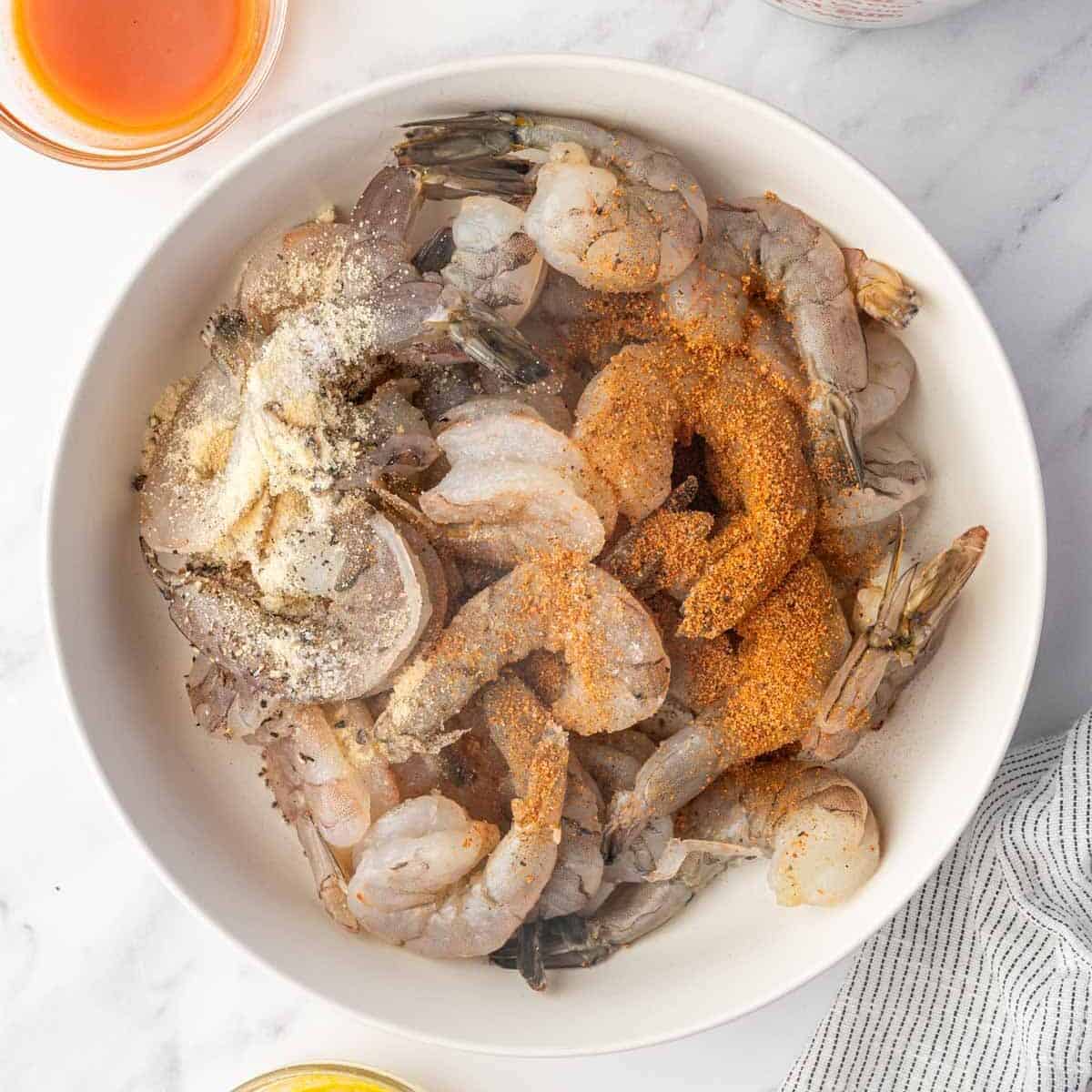 Shrimp seasoned with cajun seasoning and other spices in a bowl.