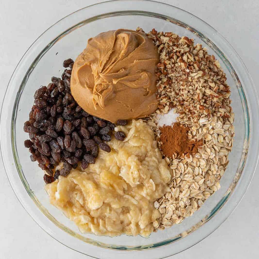 Cinnamon raisin oatmeal bar ingredients in a clear glass bowl.