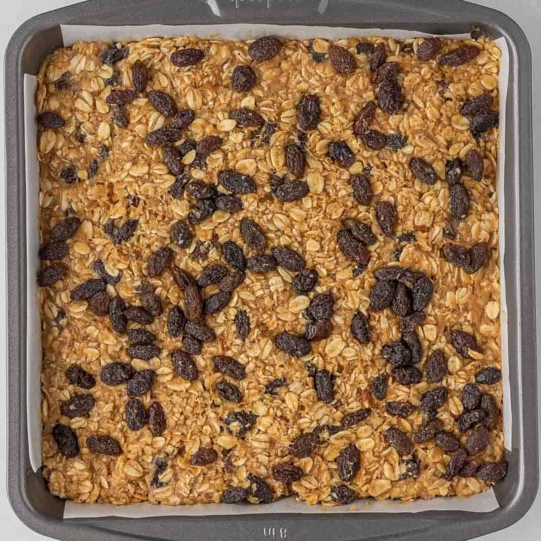 Oatmeal bars topped with raisins in a pan.
