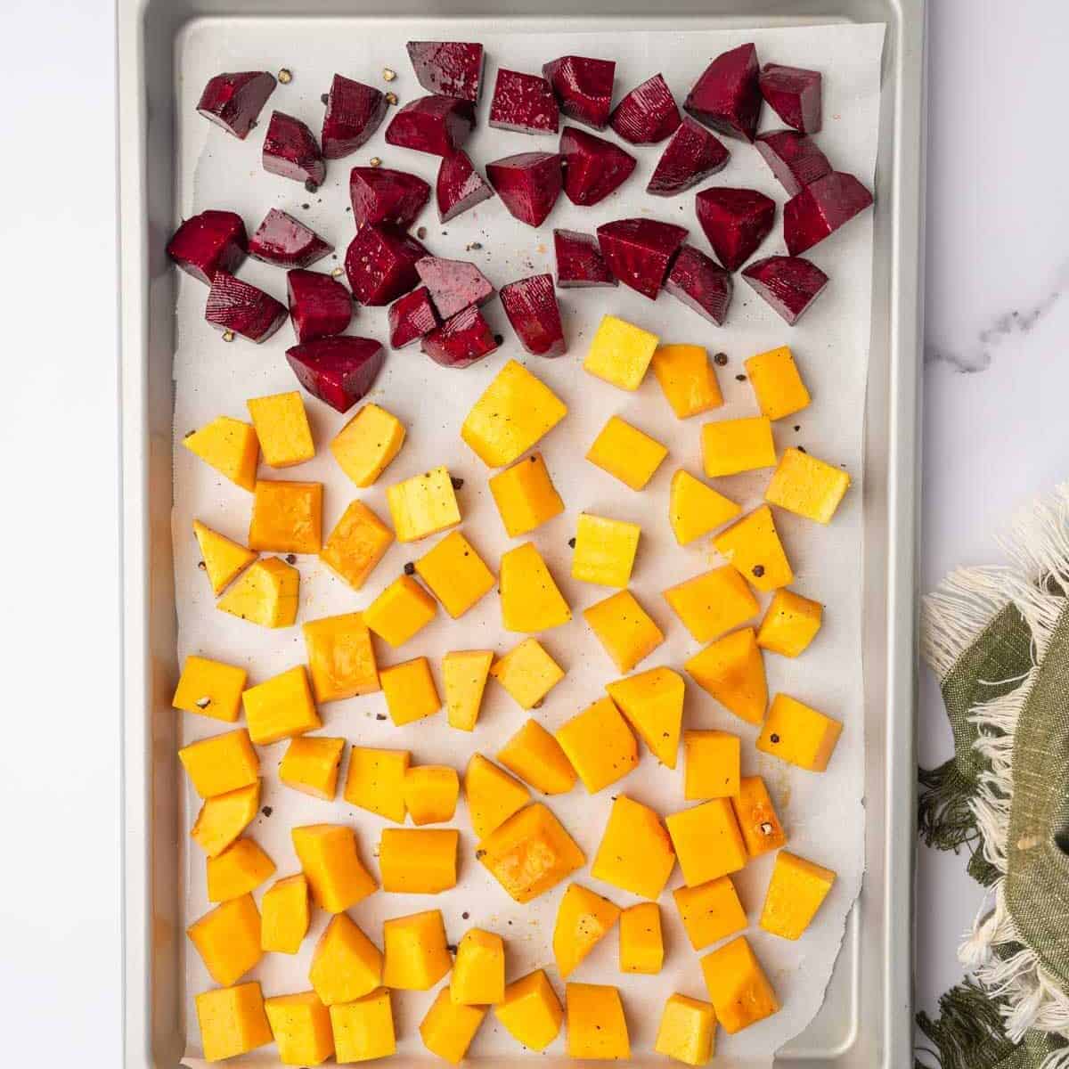 Beets and butternut squash are roasted on a baking tray.