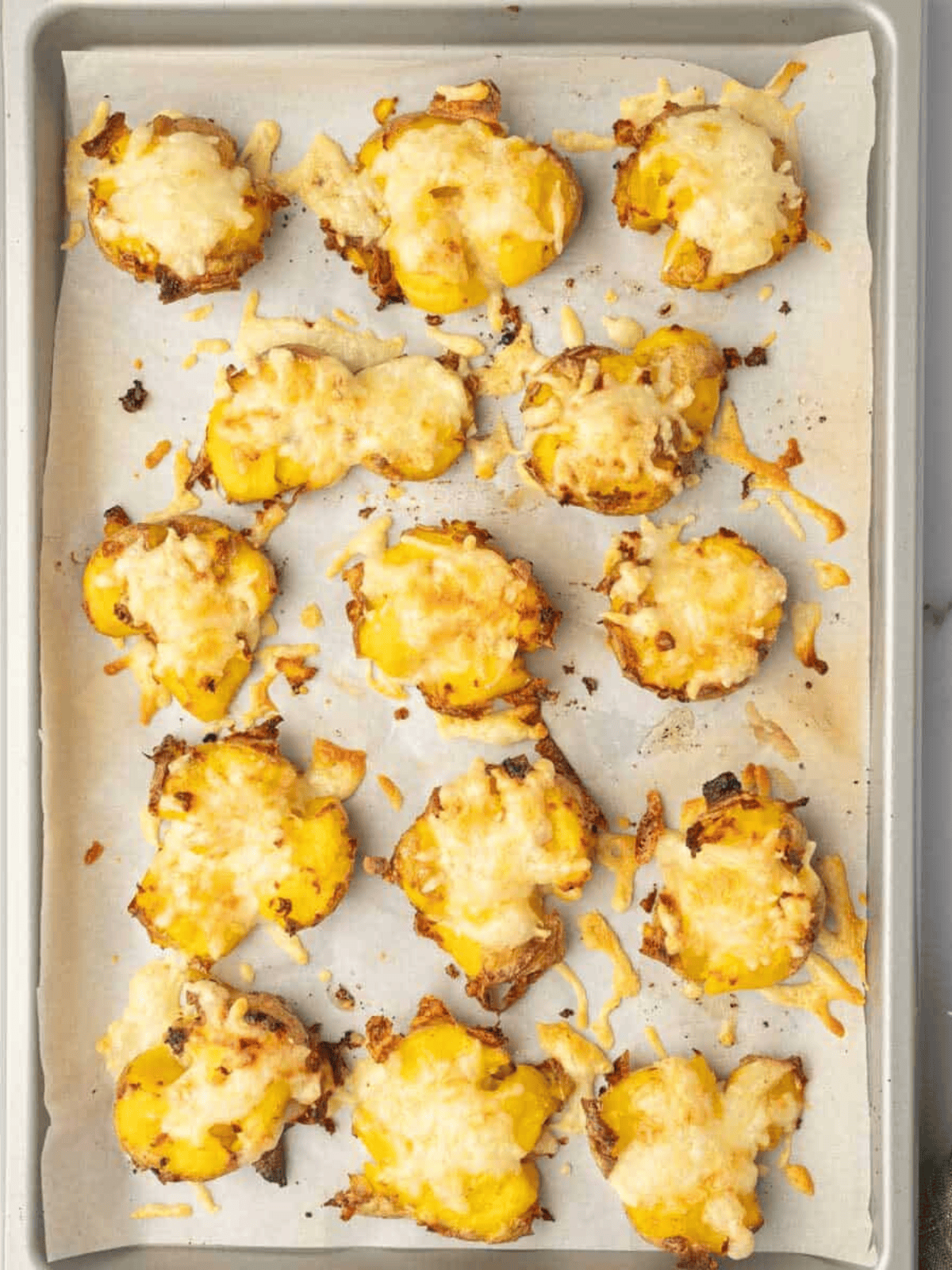 Close-up of gooey melted mozzarella stretching between golden smashed potatoes with fresh chives.