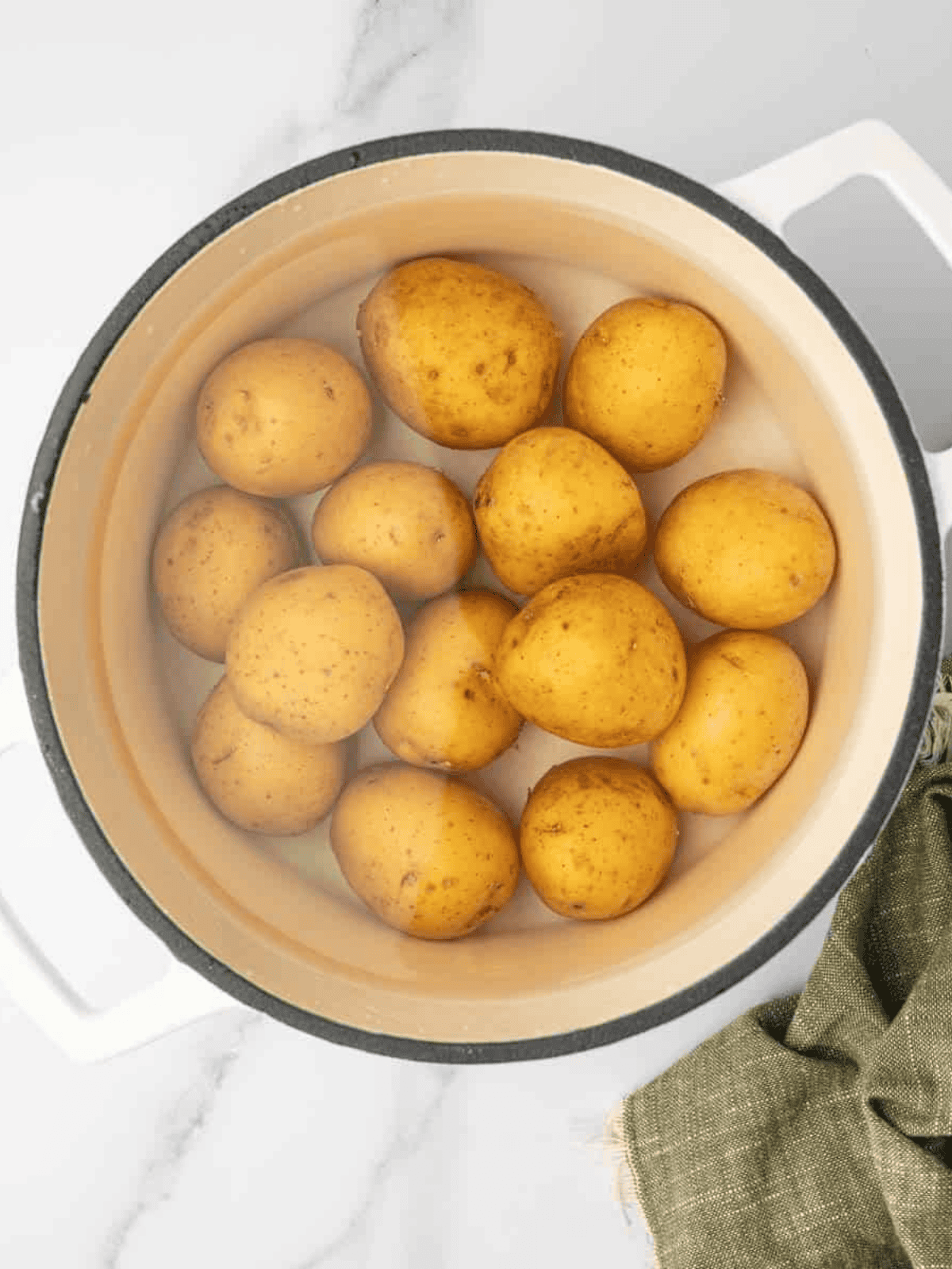 Whole Yukon gold potatoes boiling in salted water in a large pot.