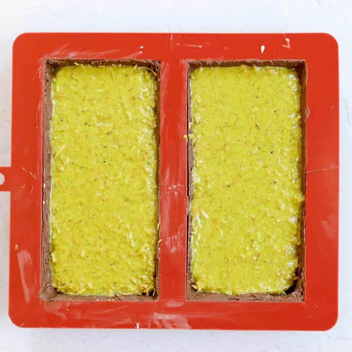 Process shot showing addition of pistachio cream kunafa into the chocolate mold.