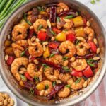 Kung Pao shrimp with bell peppers and peanuts in a skillet.