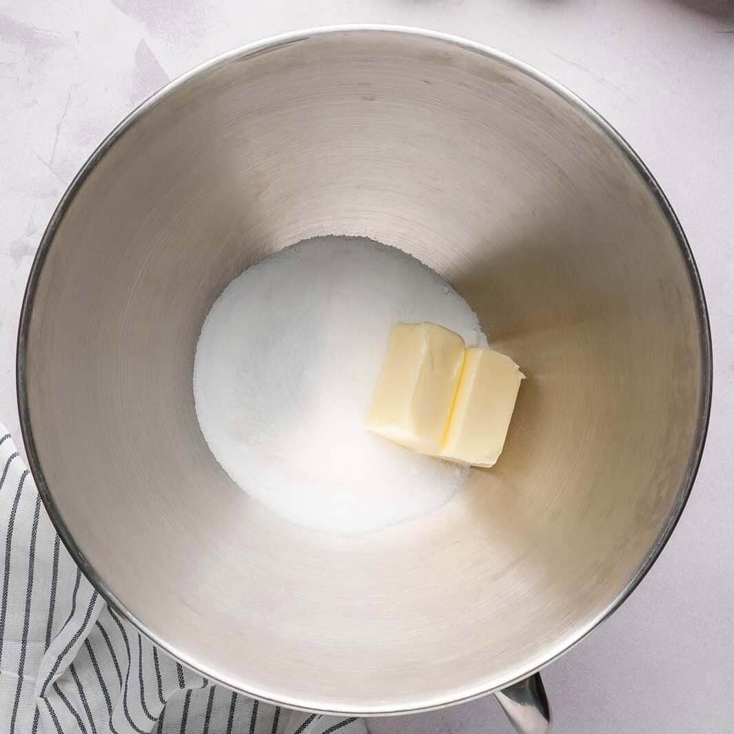 Creaming softened butter and granulated sugar in a stand mixer to create a light and airy sponge cake base.