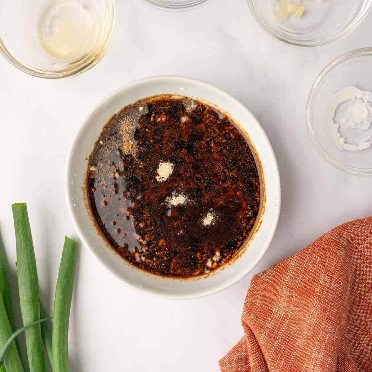 Whisking the ingredients for homemade teriyaki sauce in a small glass bowl until smooth.