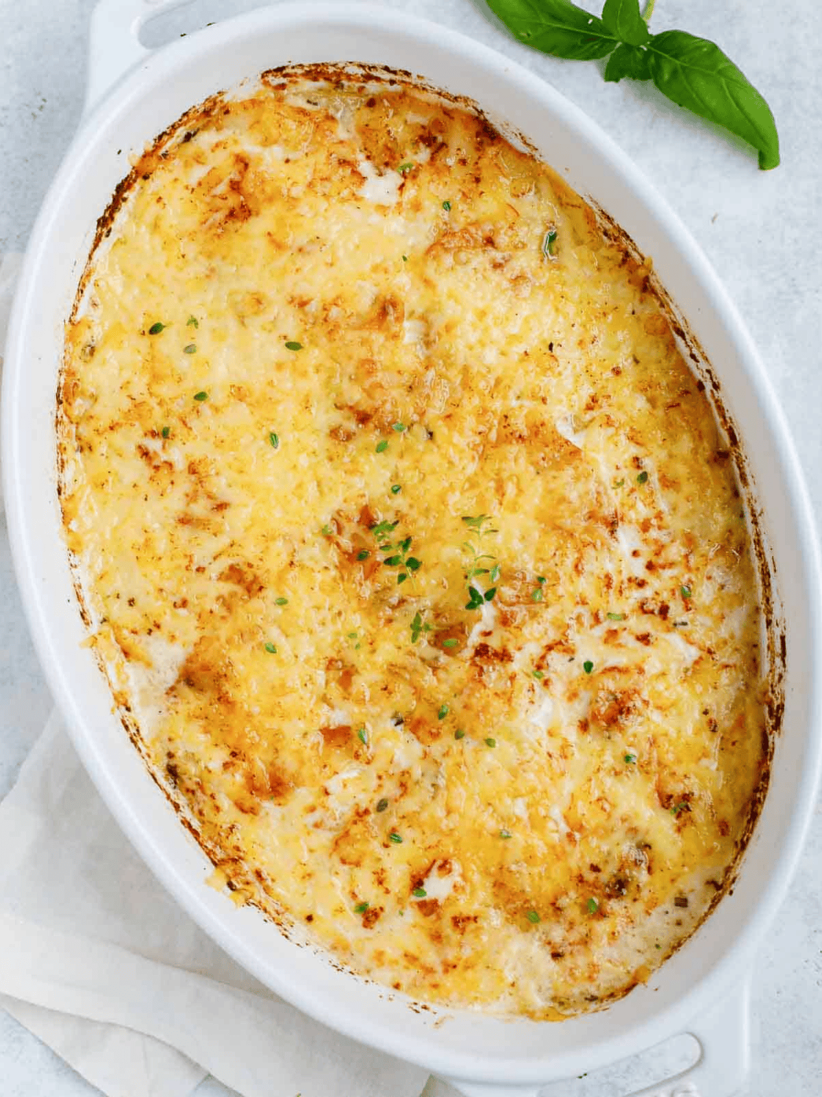 Baked potatoes with a golden cheese topping and fresh herbs.
