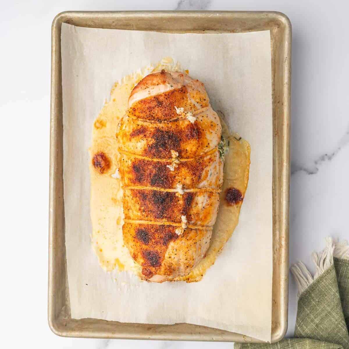 Baked turkey roll with a browned seasoned crust on a lined tray.