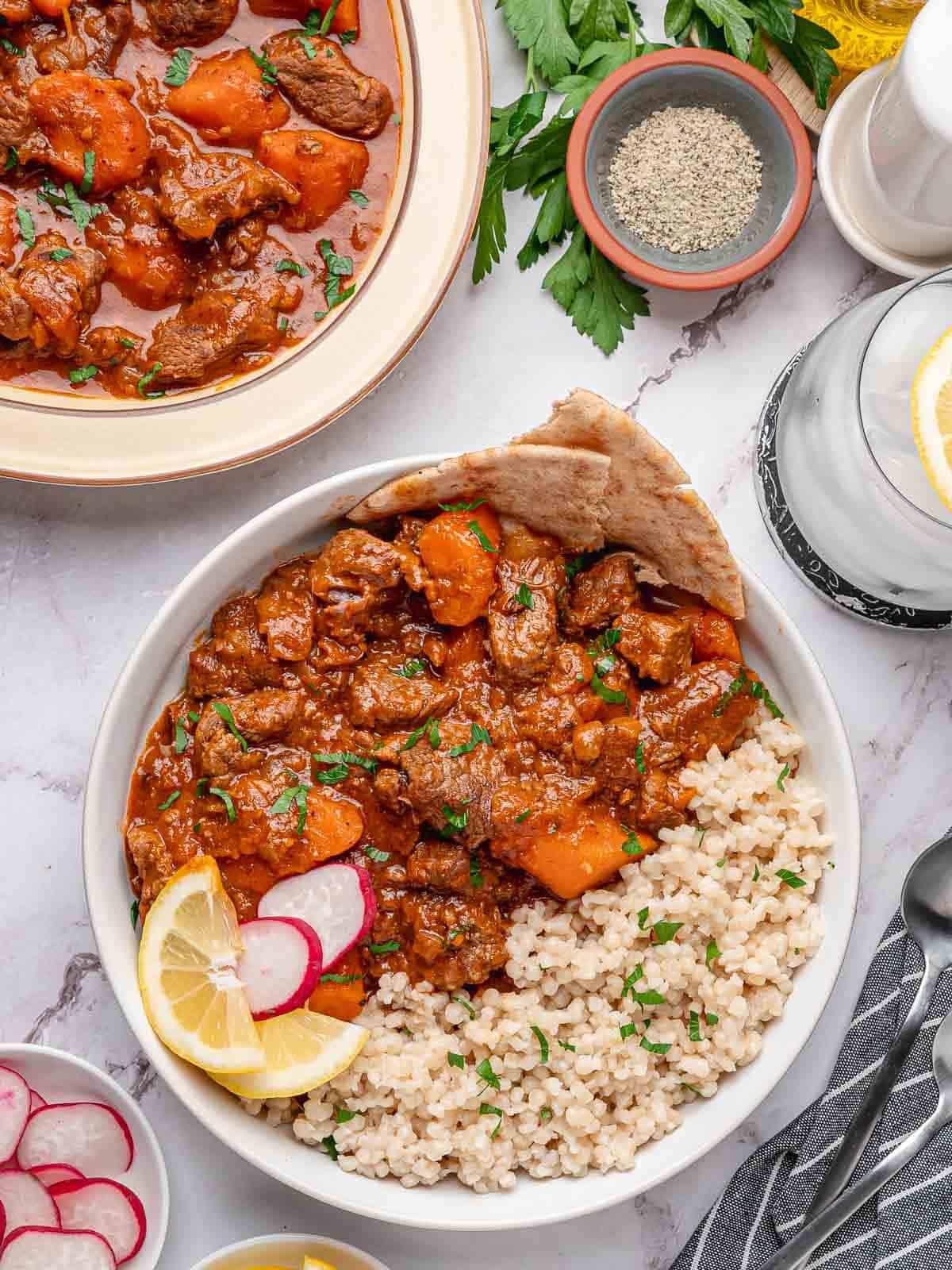 Beef stew served with couscous, flatbread and lemon.