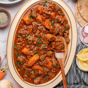 Beef stew with tomato sauce, carrots, and tender beef served on a platter.