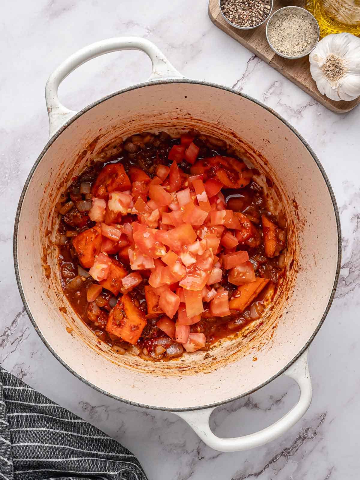 Adding diced tomatoes to the beef stew.