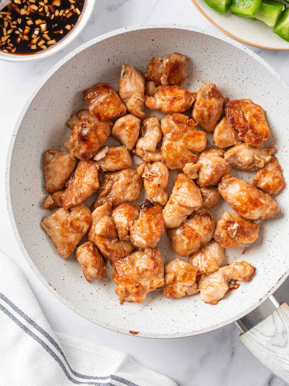 Pieces of chicken seared until golden in a skillet.