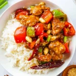 Kung Pao chicken with bell peppers, peanuts, and dried chilies served over white rice.