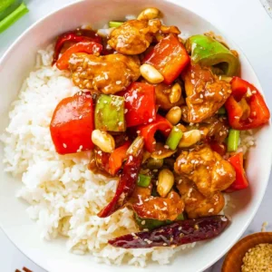 Kung Pao chicken with bell peppers, peanuts, and dried chilies served over white rice.