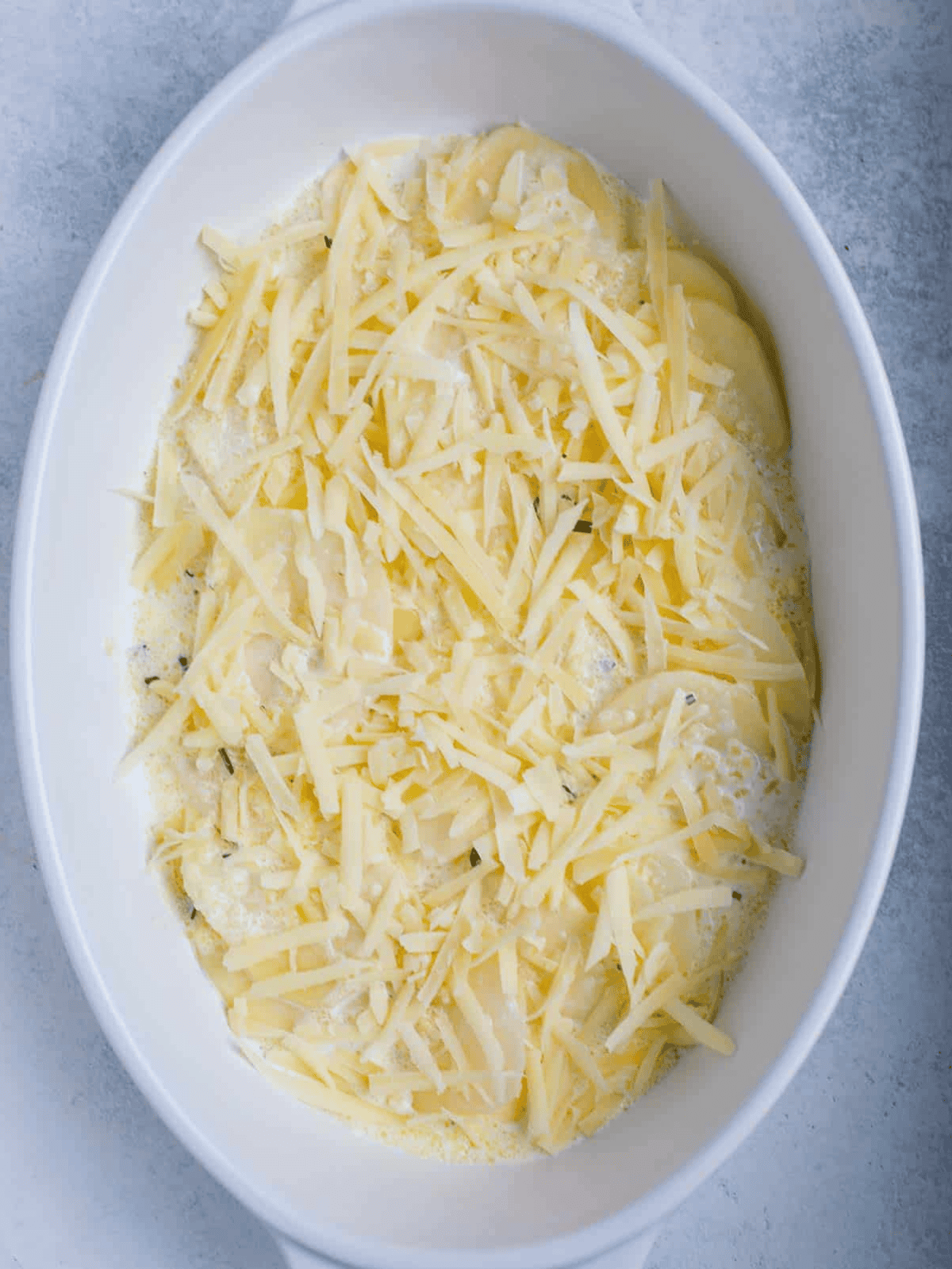 Potato layers topped with shredded cheese and cream.