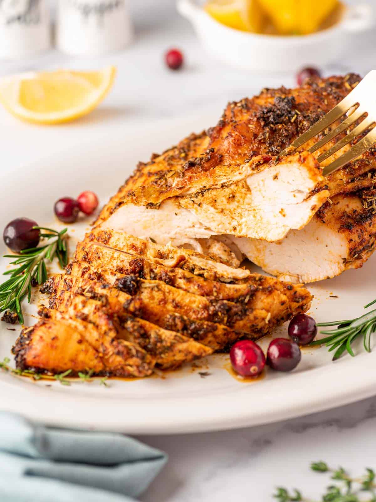 Boneless turkey sliced through and a slice lifted with a fork.
