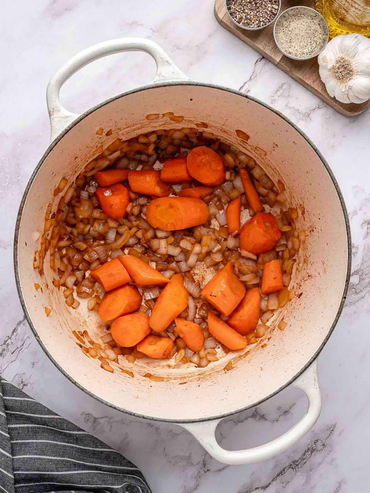 Carrots and onions sautéing in a pot.