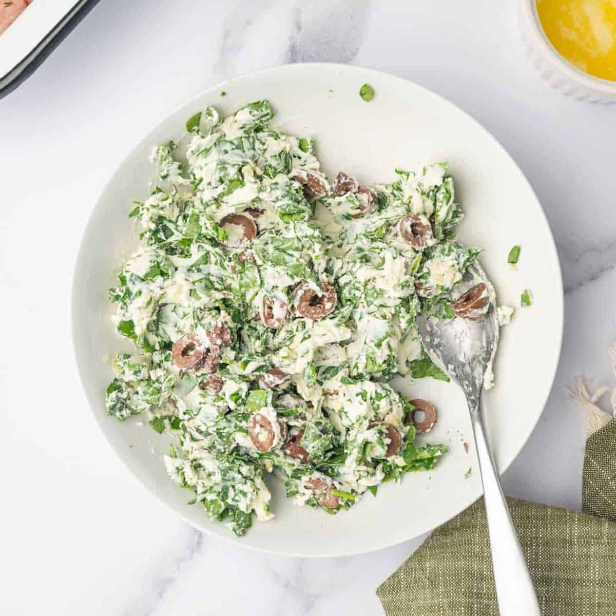 Creamy spinach and Kalamata olive filling mixed in a bowl.