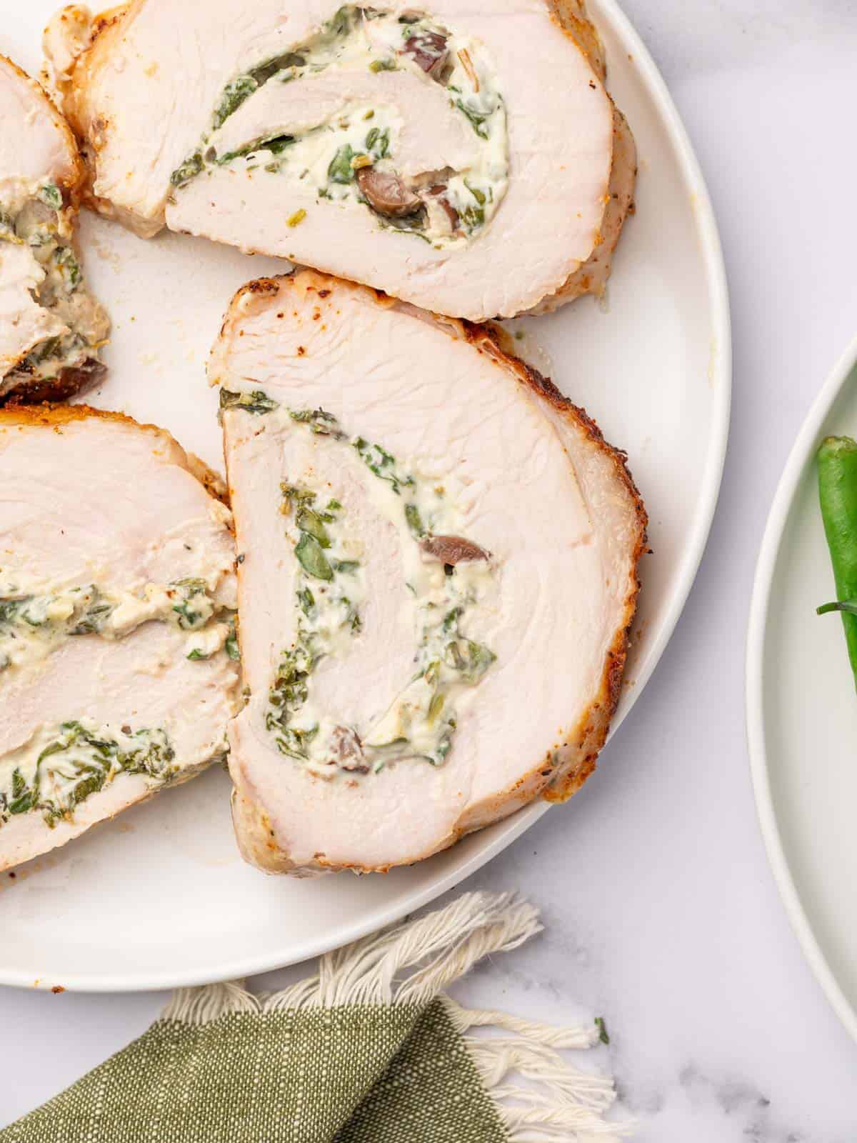 Golden turkey roll served on a platter with fresh rosemary.