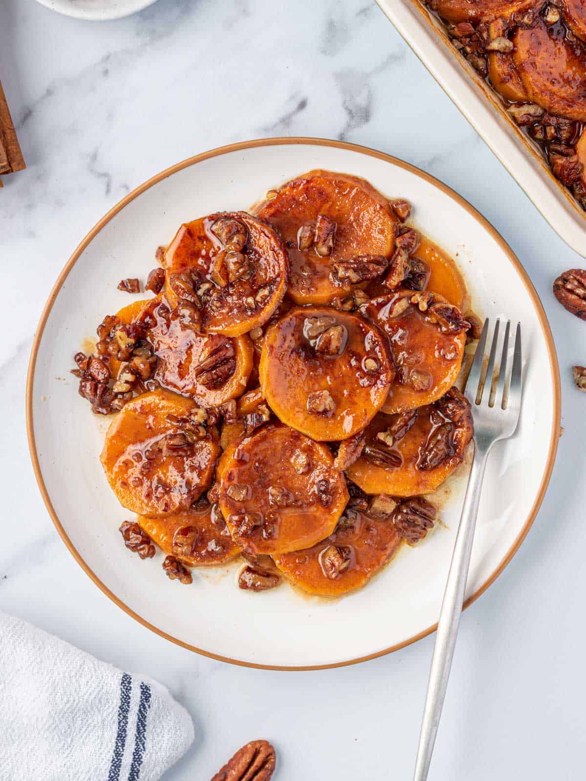 Candied sweet potatoes with pecans and brown sugar sauce served on a plate.