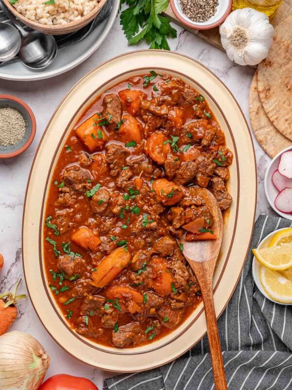 Tomato Beef Stew with carrots and parsley on a serving platter.
