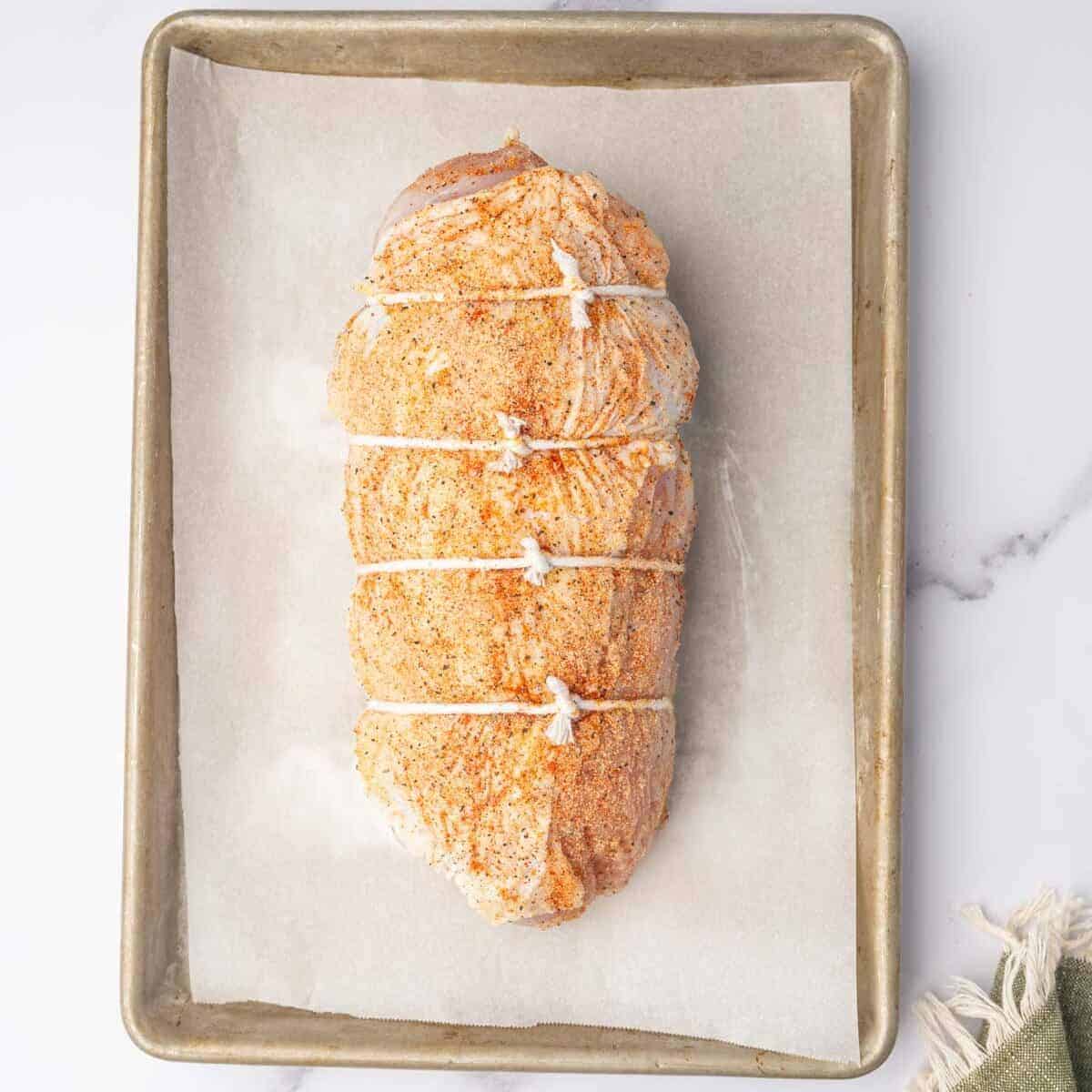 Seasoned turkey roll secured with kitchen twine before roasting.
