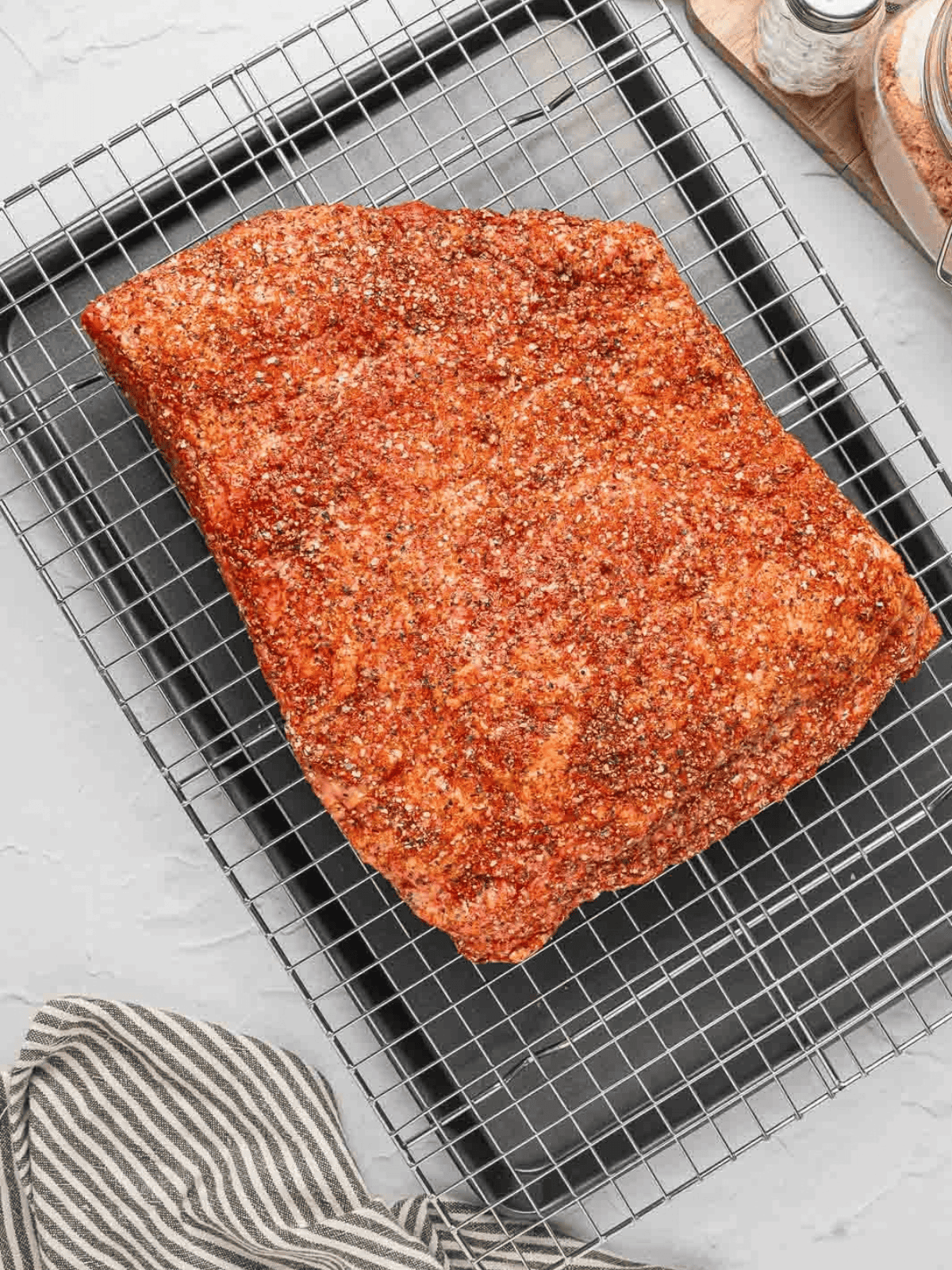 Seasoned brisket resting fat-side up on a wire rack.
