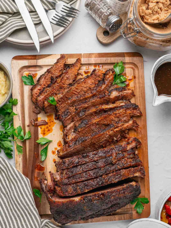 Sliced beef brisket arranged on a wooden cutting board with fresh parsley.