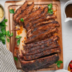 Juicy beef brisket slices arranged on a wooden board with fresh parsley.