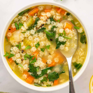 Overhead view of stelline pasta soup in a bowl with a spoon.